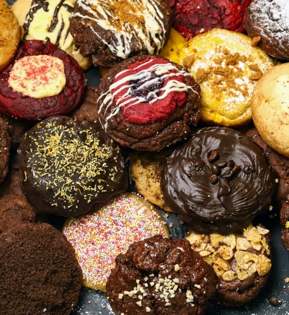 A close-up shot of an assortment of diverse, freshly baked cookies featuring various colorful toppings and frostings.